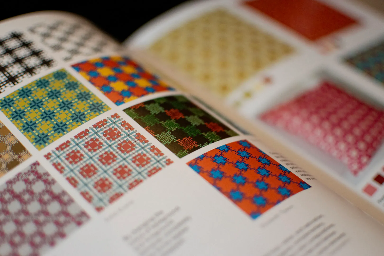 A close-up of a book or catalog featuring a collection of colorful geometric patterns, likely showcasing textile designs.